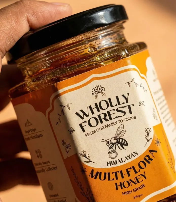 Artisanal luxury gift box hamper featuring Wholly Forest raw honey glass jars, wooden dipper, and natural packaging